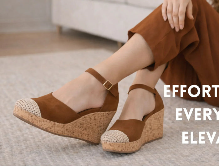 Brown wedge sandals worn by a person sitting on a carpeted floor with text 'EFFORTLESS. EVERYDAY. ELEVATED.'